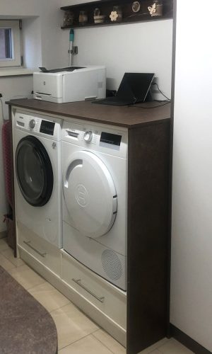 Hauswirtschaftsraum mit einem weißen Aufbewahrungsschrank und einem Korpus um die Waschmaschine und den Trockner